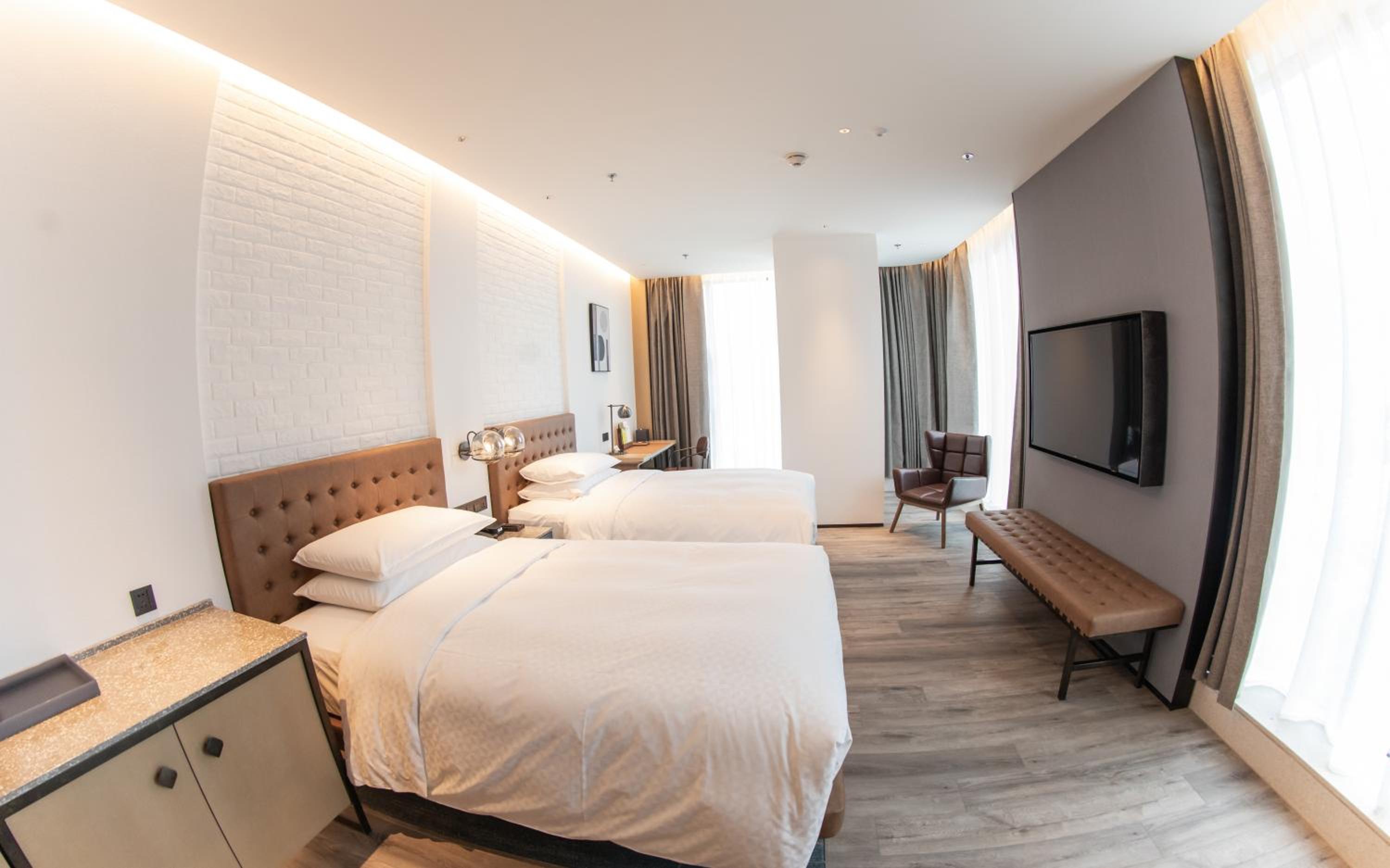 Corner guest room with two double beds and city view