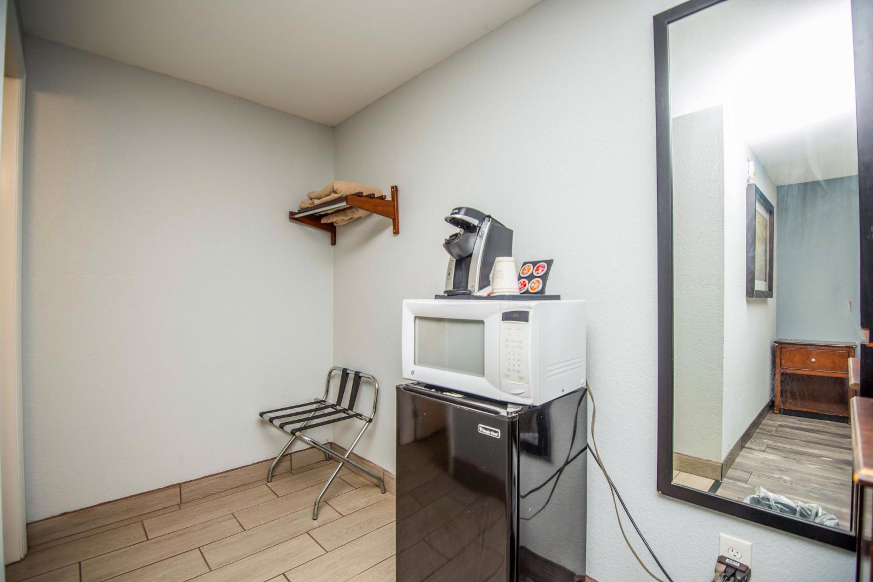 Hotel room corner with mini-fridge, microwave, coffee maker, and folding chair