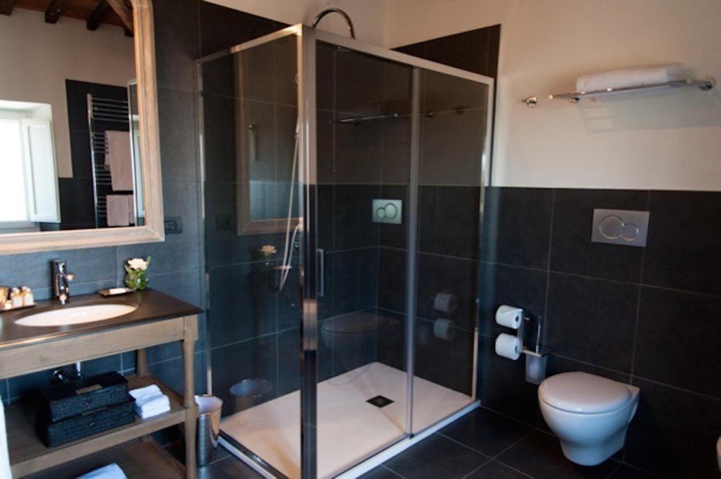 bathroom with a toilet, sink, and shower stall