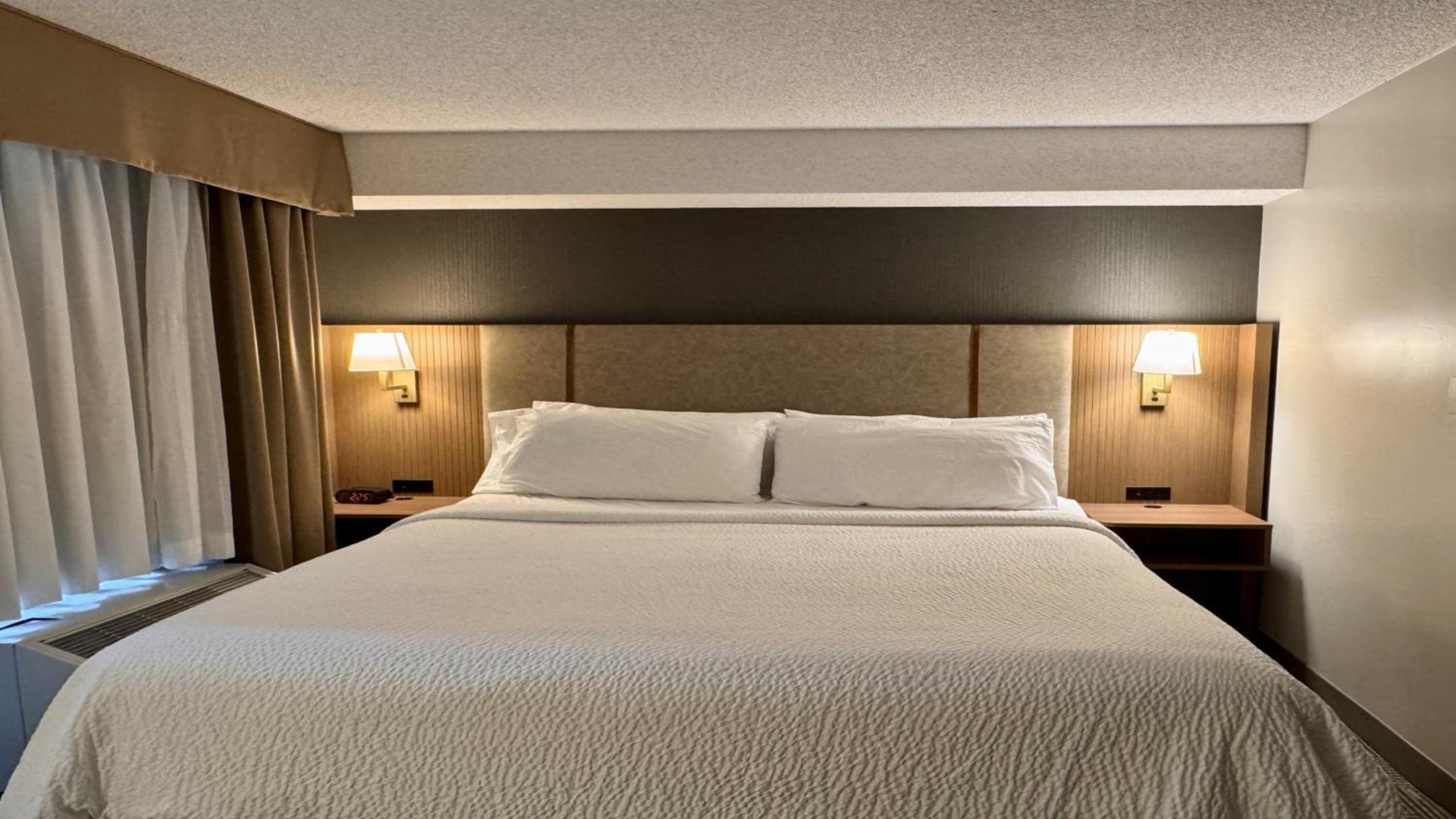 hotel room with a bed and two lamps on either side of the bed