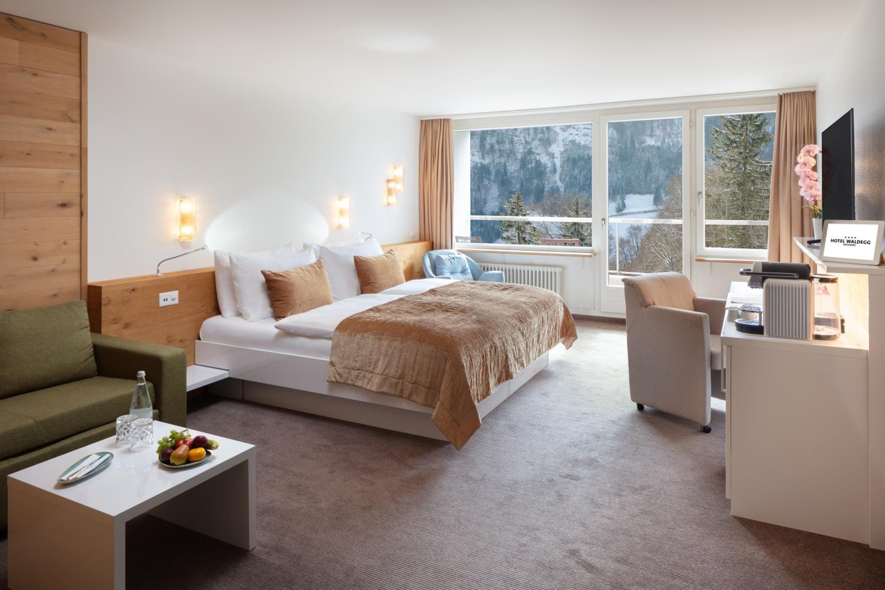 hotel room with a bed, couch, coffee table and television