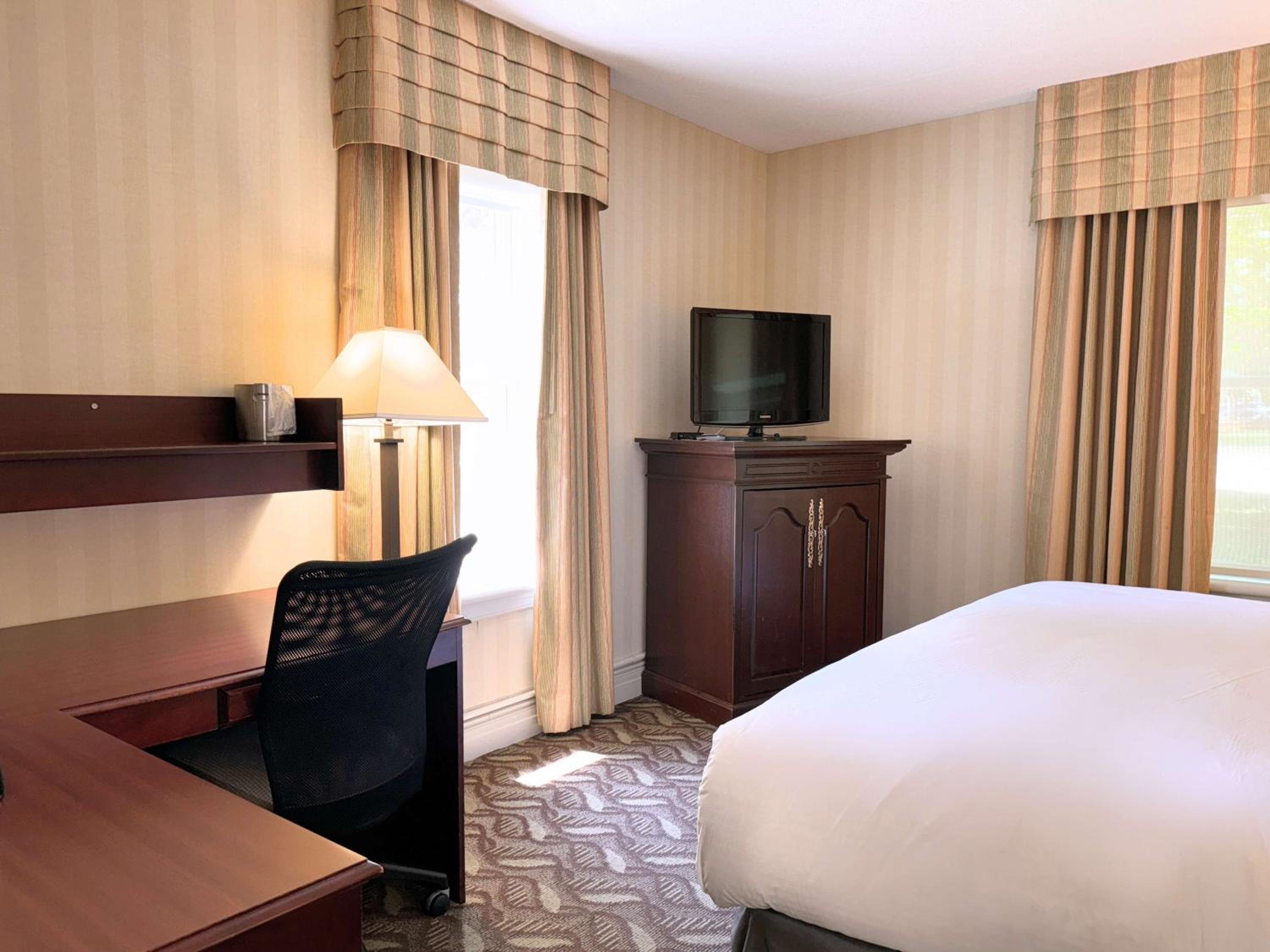 hotel room with a bed, desk, and television