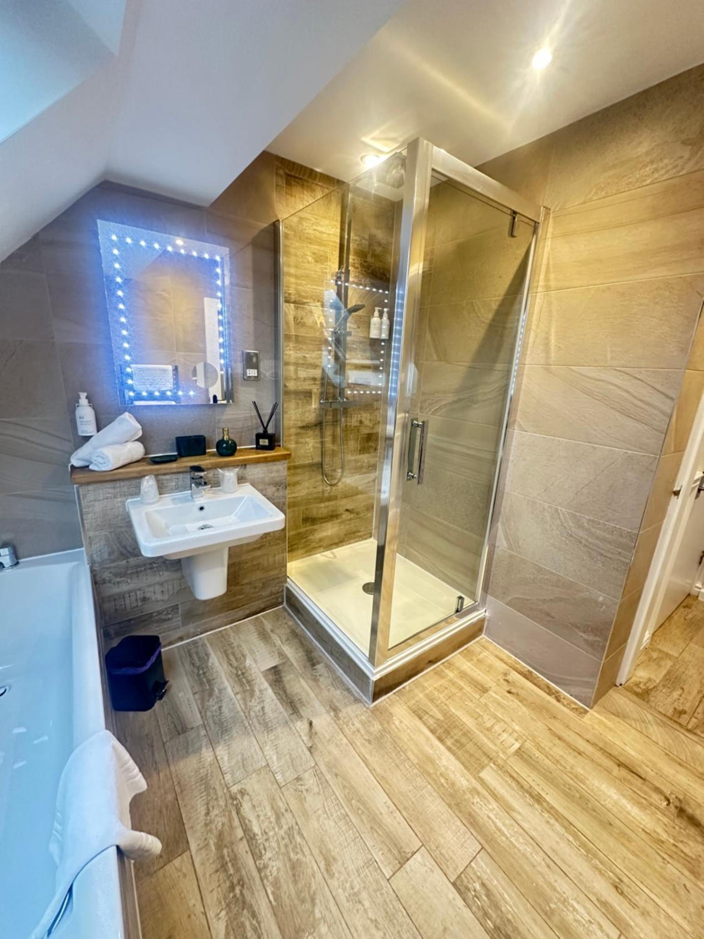 Attic bathroom with glass shower, sink, bathtub and wood-effect tiles