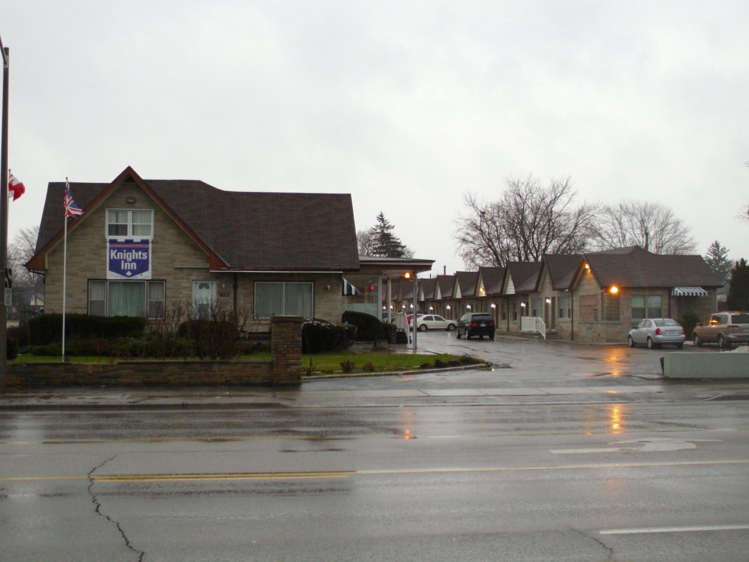 rain soaked street with houses and cars in the background
