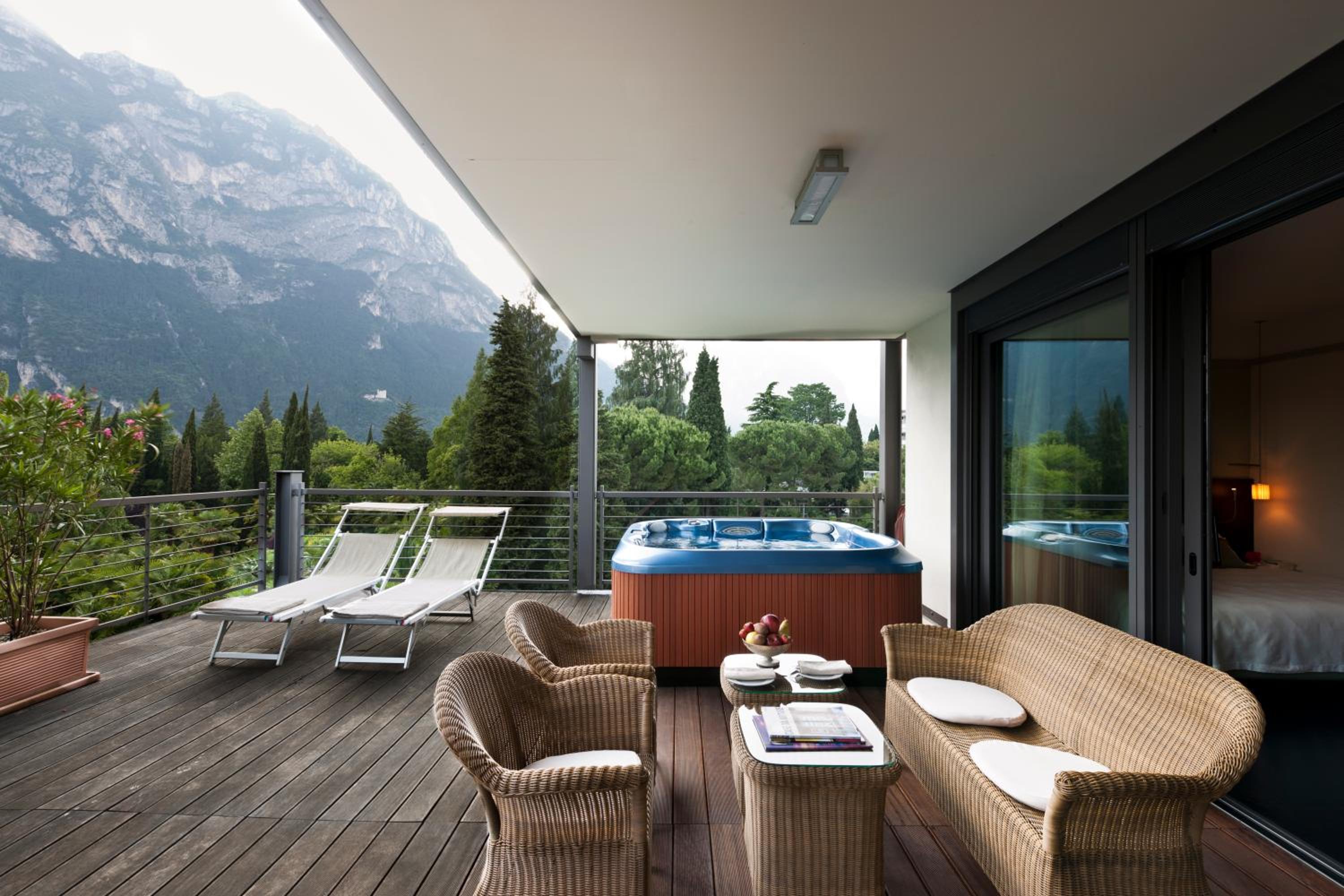 Outdoor terrace with a blue hot tub, wicker seating, and a mountain view.