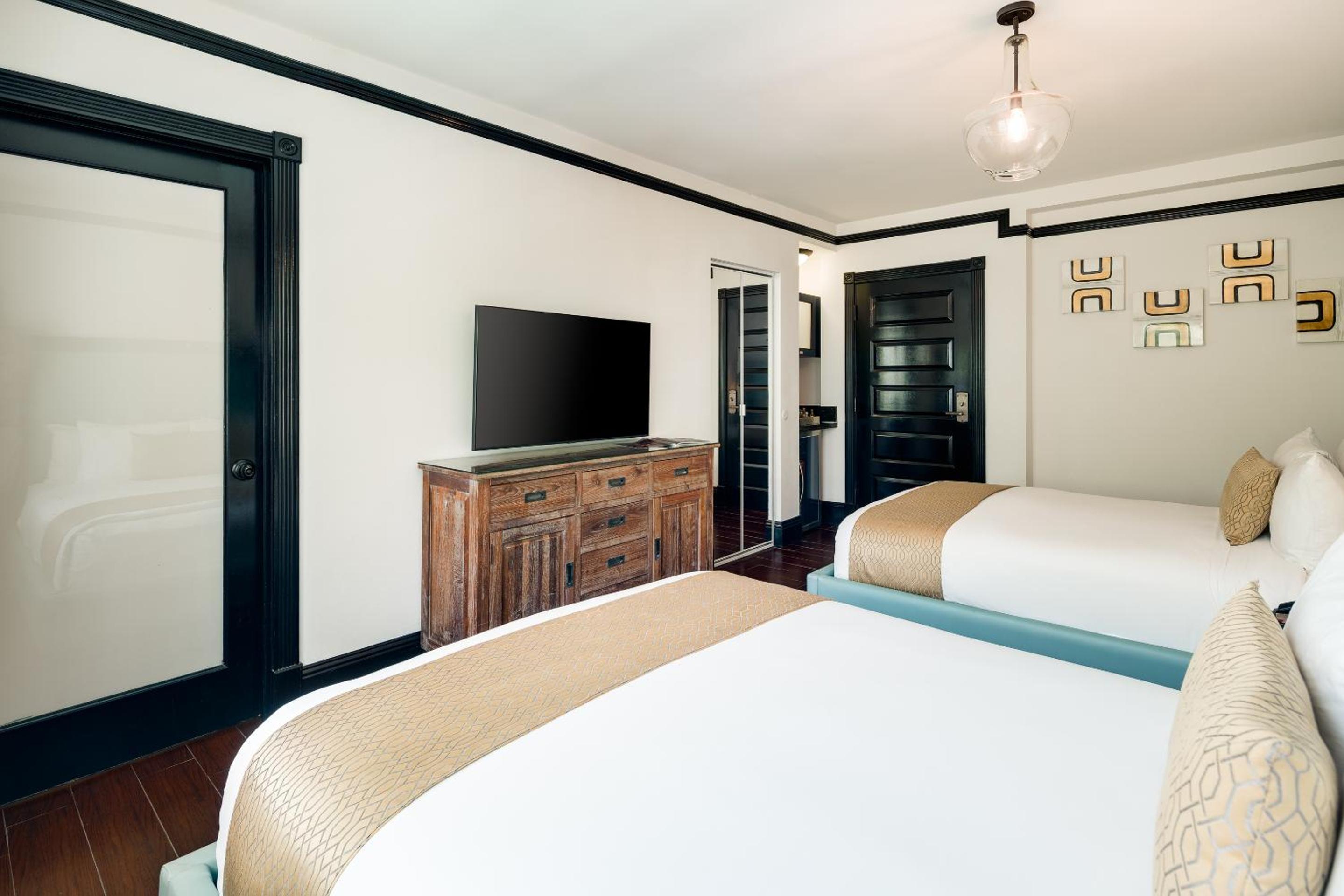 Hotel room with two beds, a wooden dresser, and a flat-screen television.