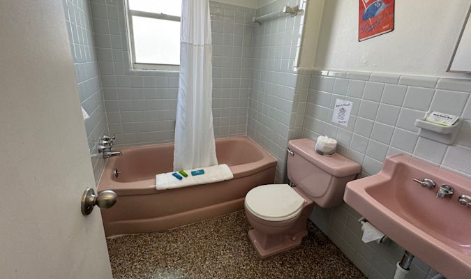 Pink bathroom with tub, toilet, and sink