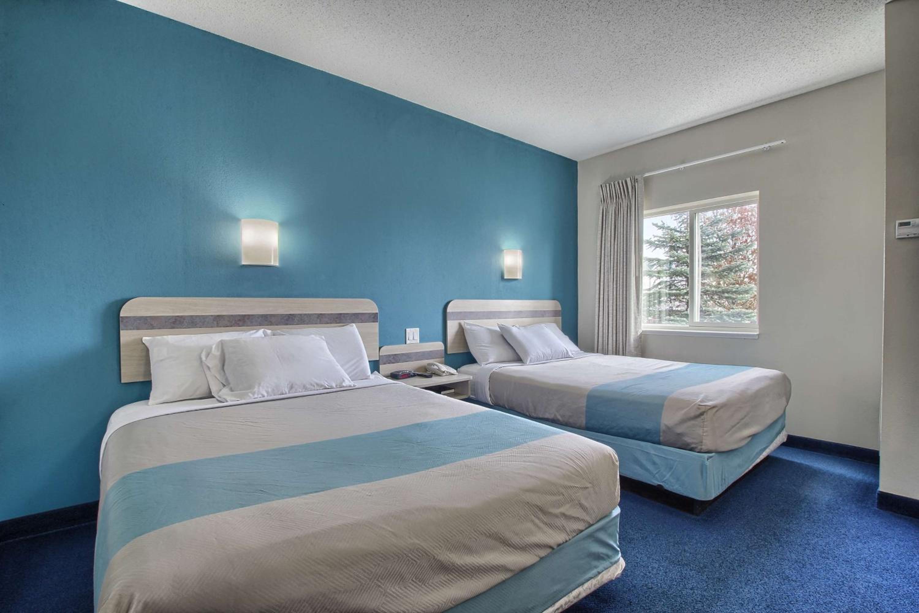 hotel room with two beds and a blue accent wall