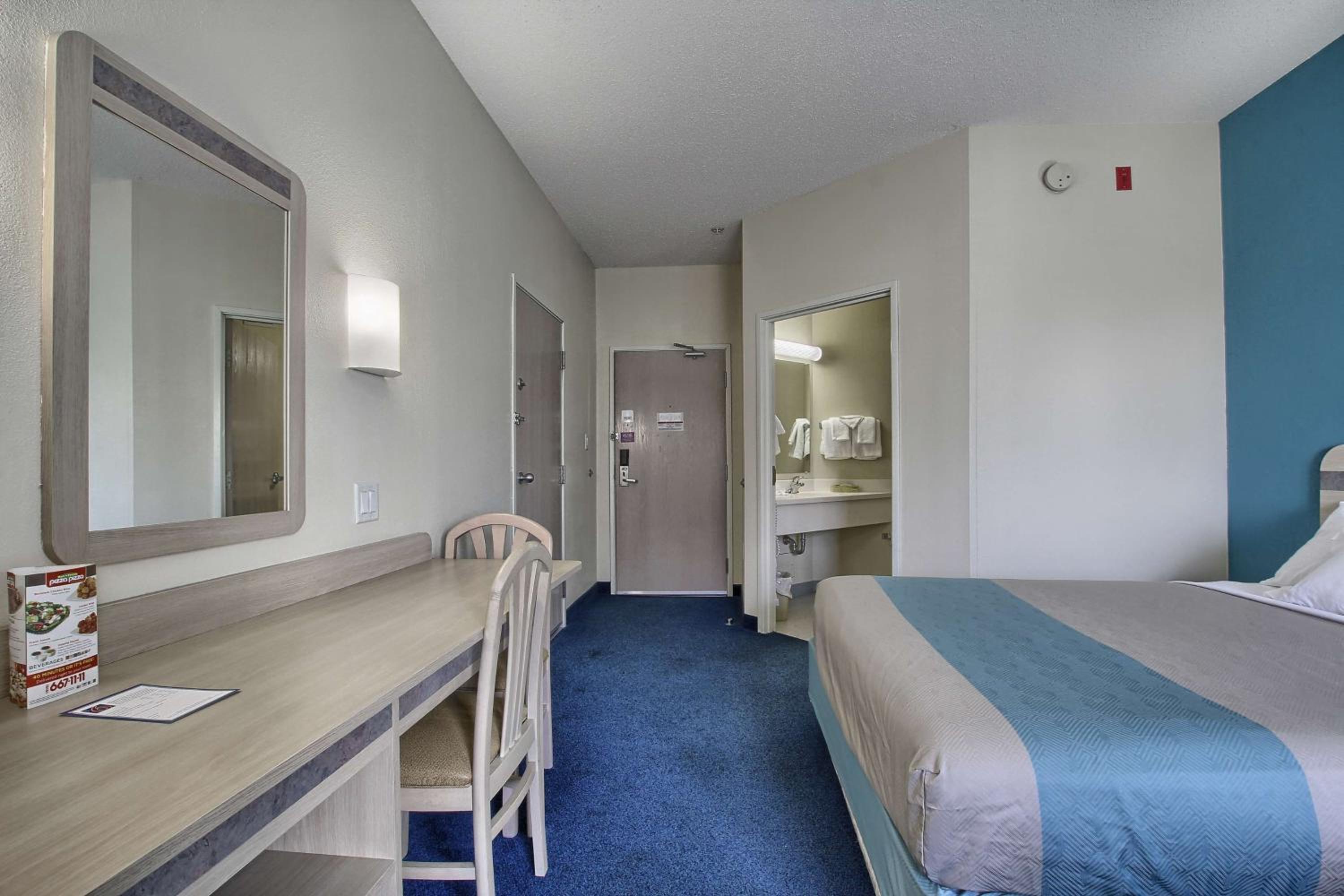 hotel room with a bed, desk, and mirror