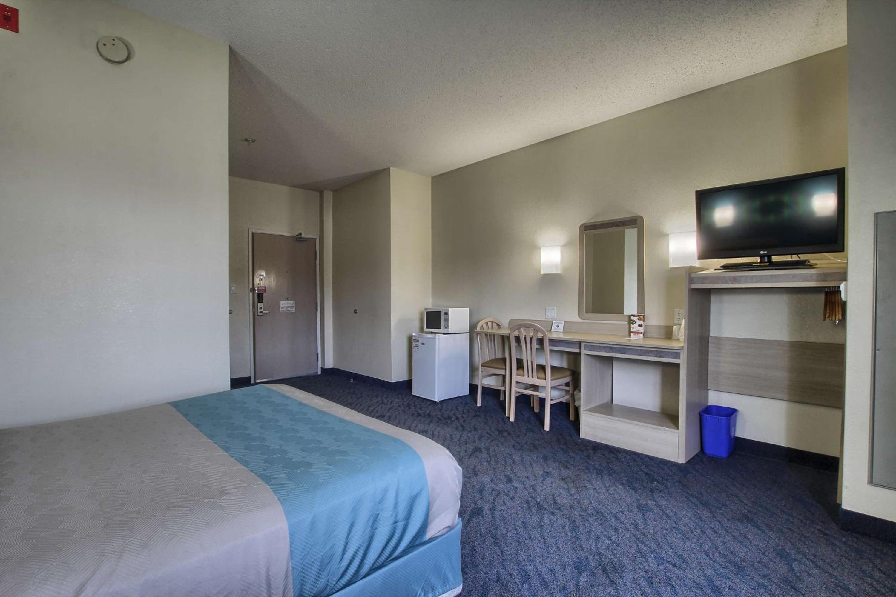 hotel room with a bed, desk, and television