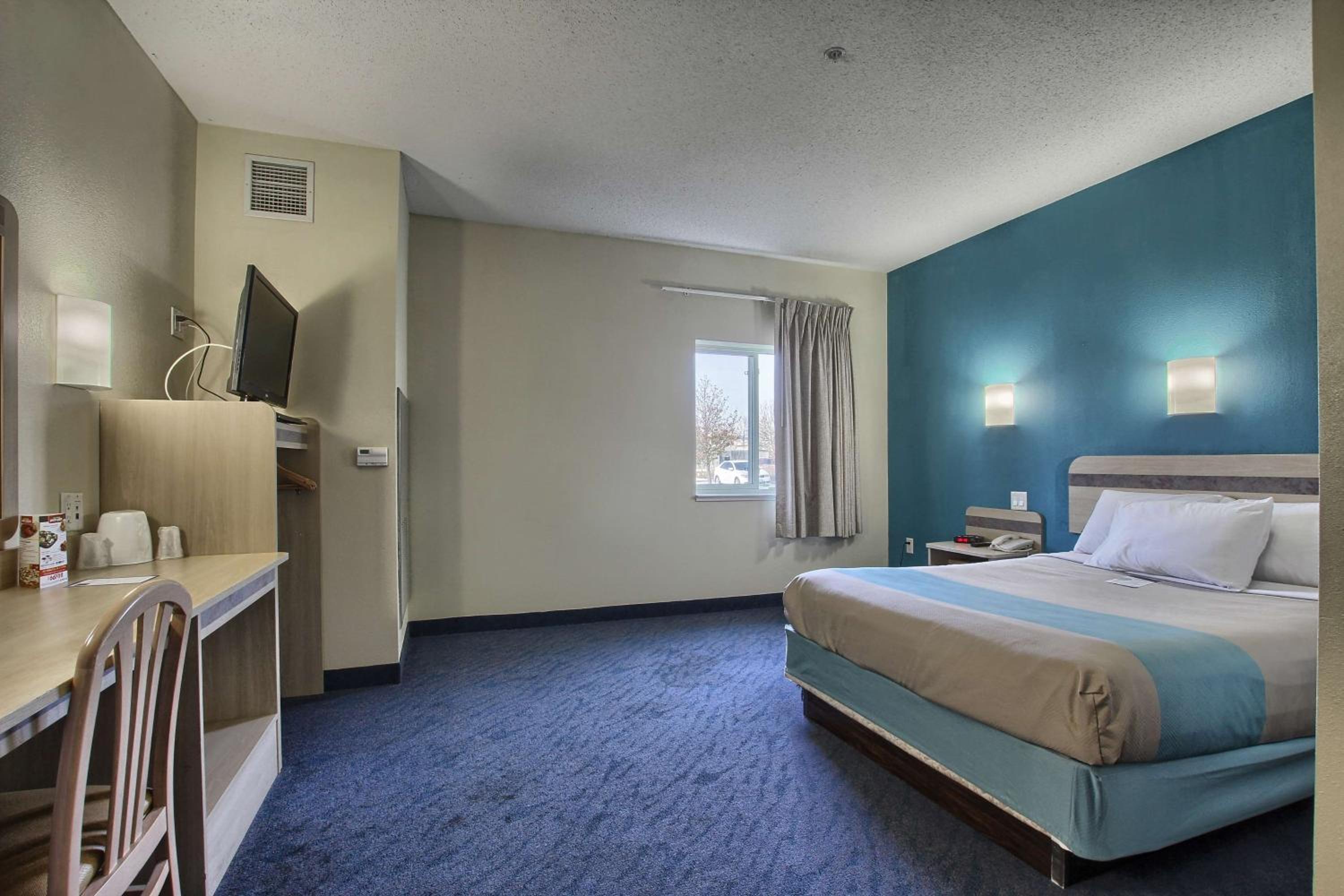hotel room with a bed, desk, and television