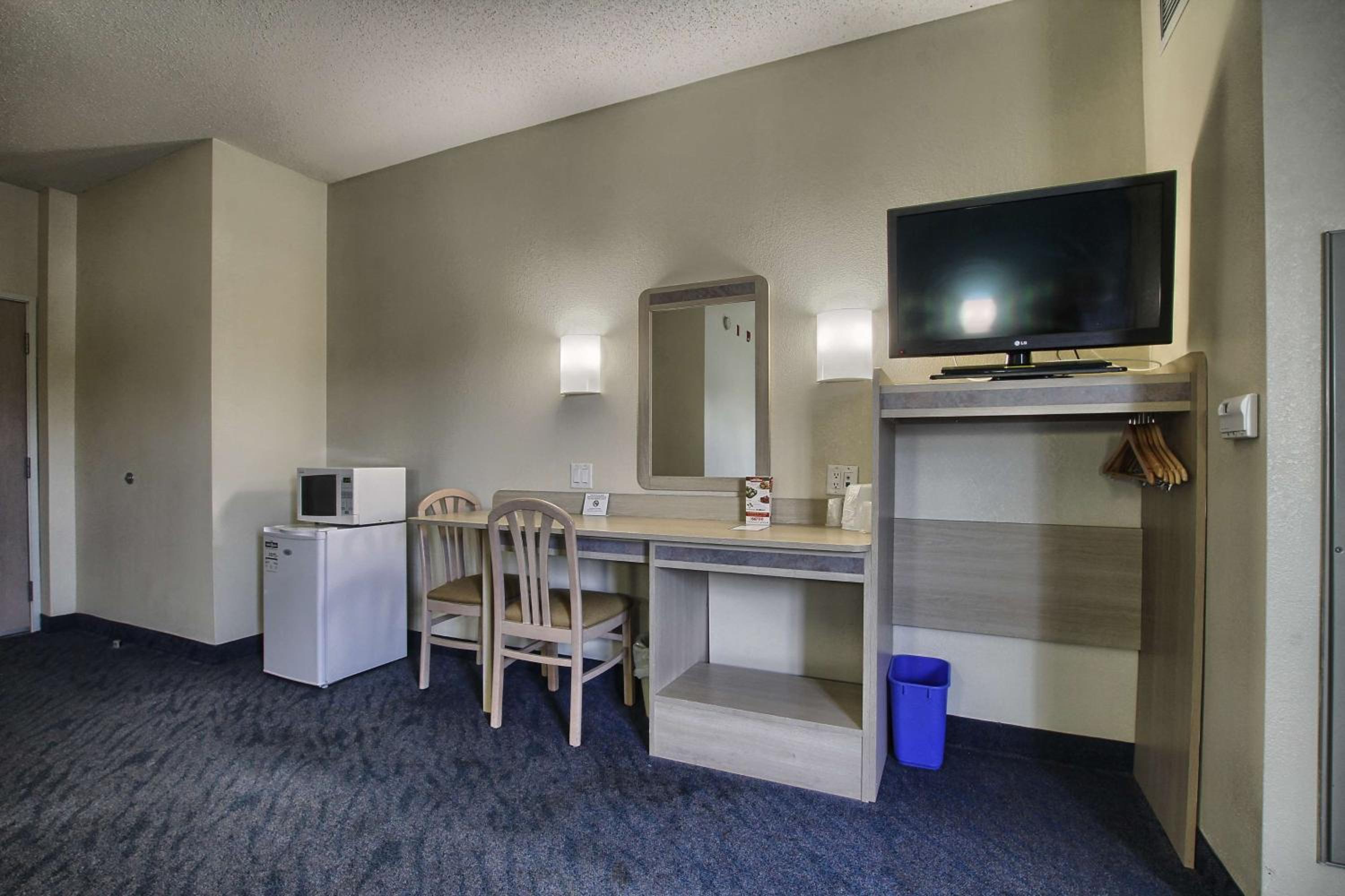 hotel room with a desk, microwave, and refrigerator