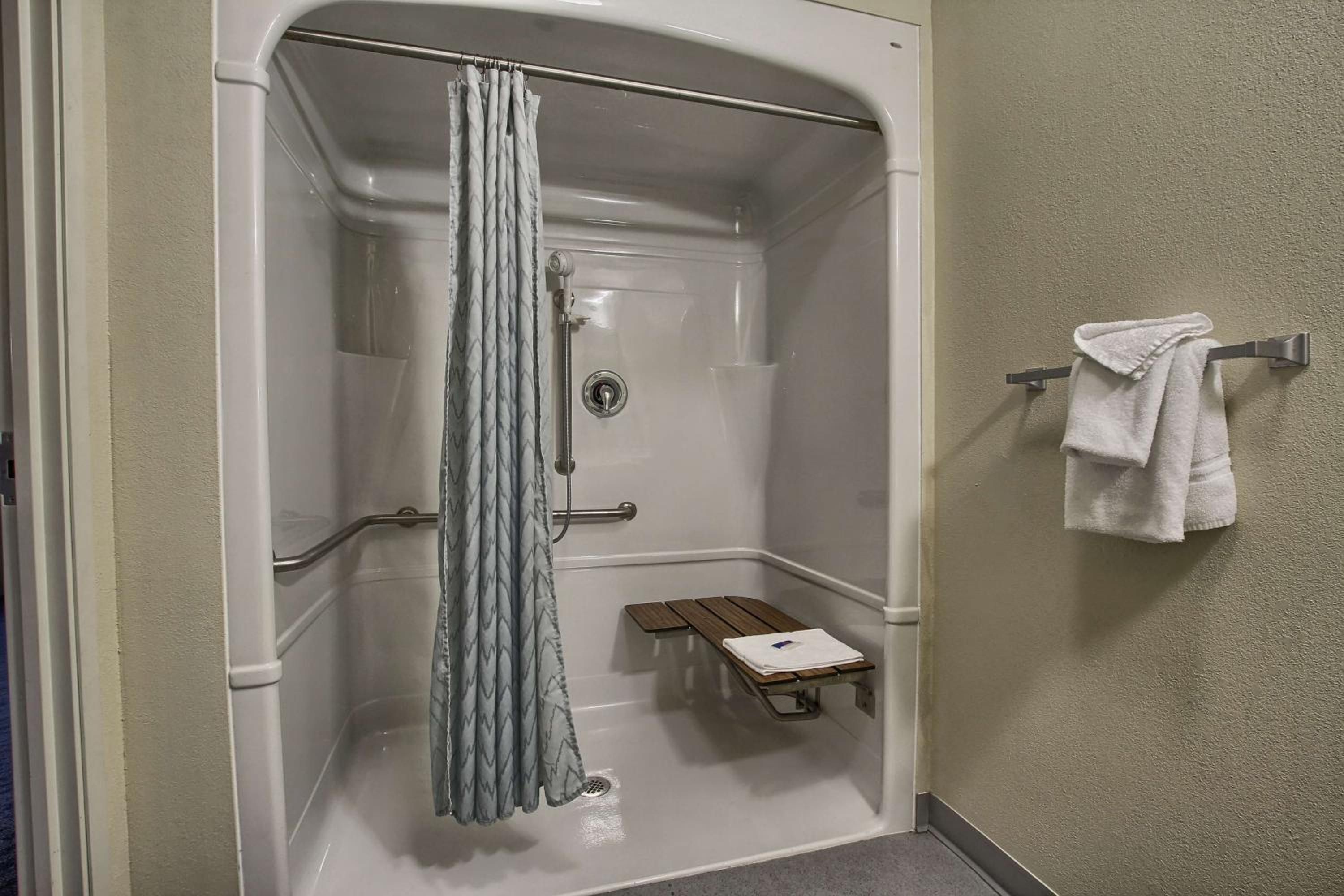 bathroom with a shower, bench, and towel rack