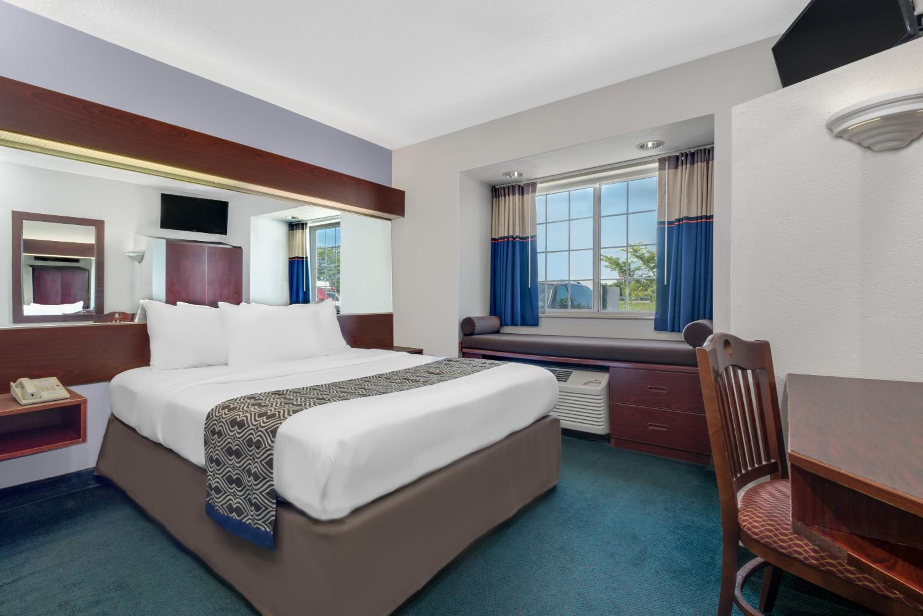 hotel room with a bed, desk, and television