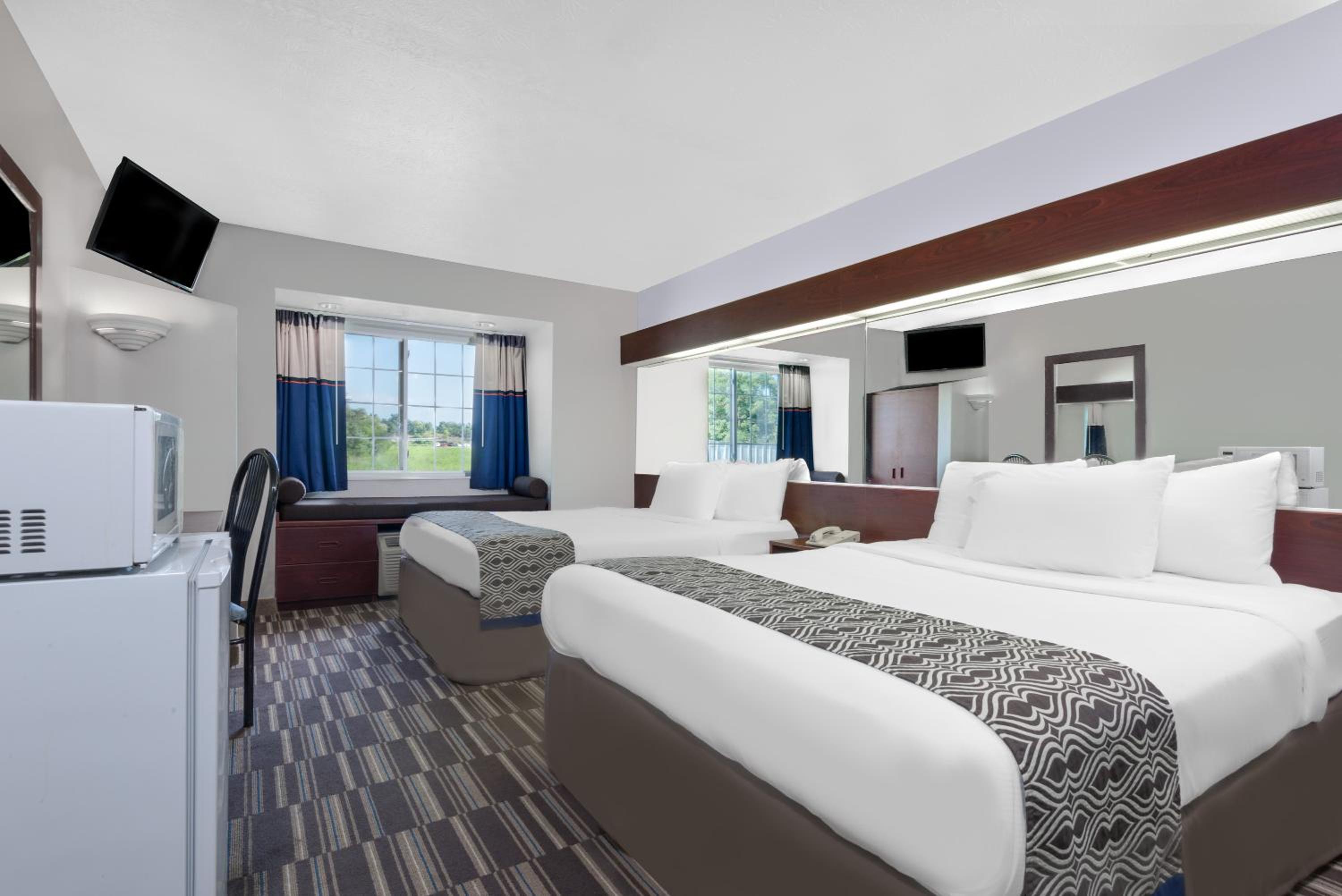hotel room with two beds and a refrigerator in it