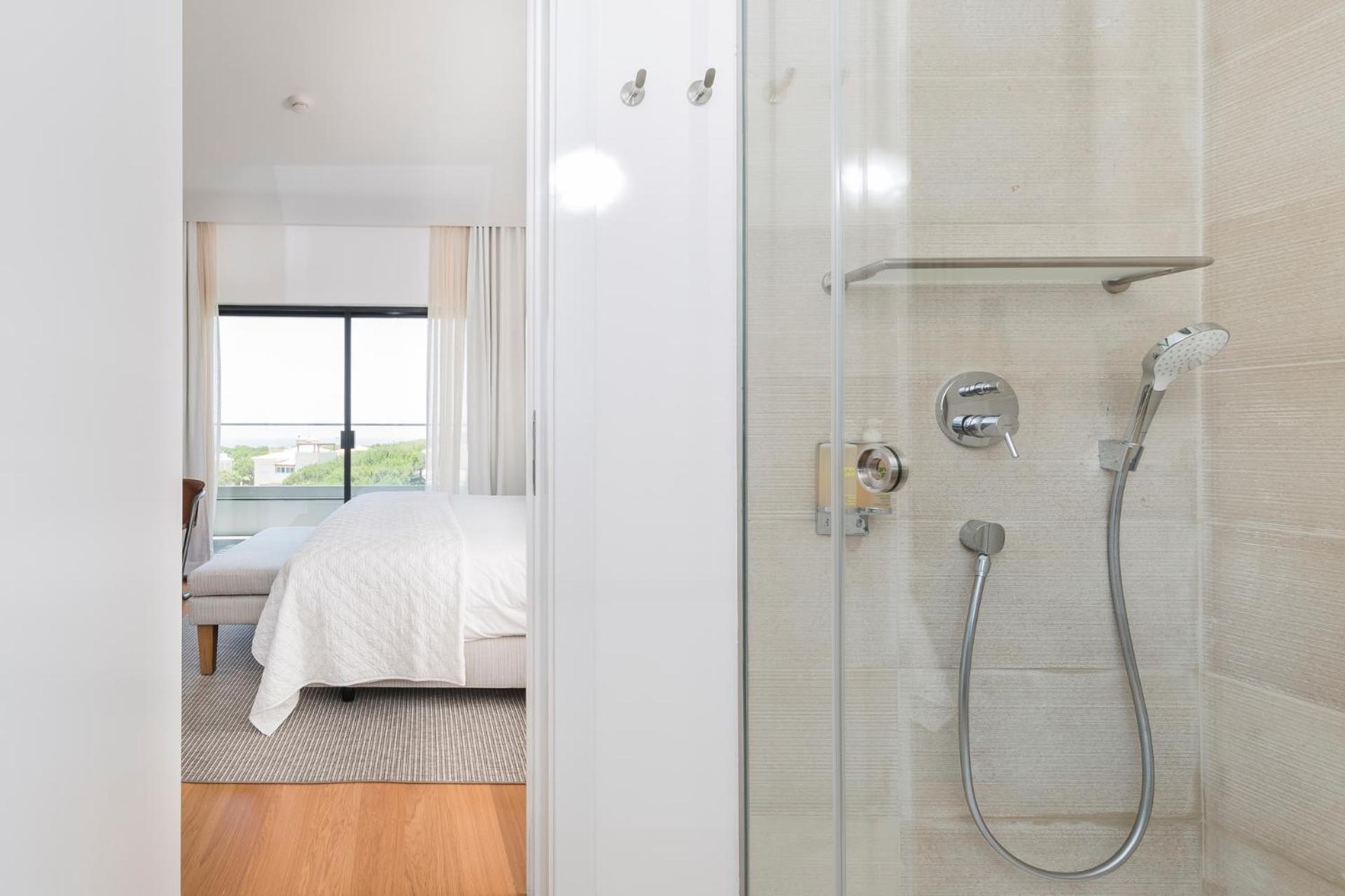 bathroom with a shower and a bed in the background