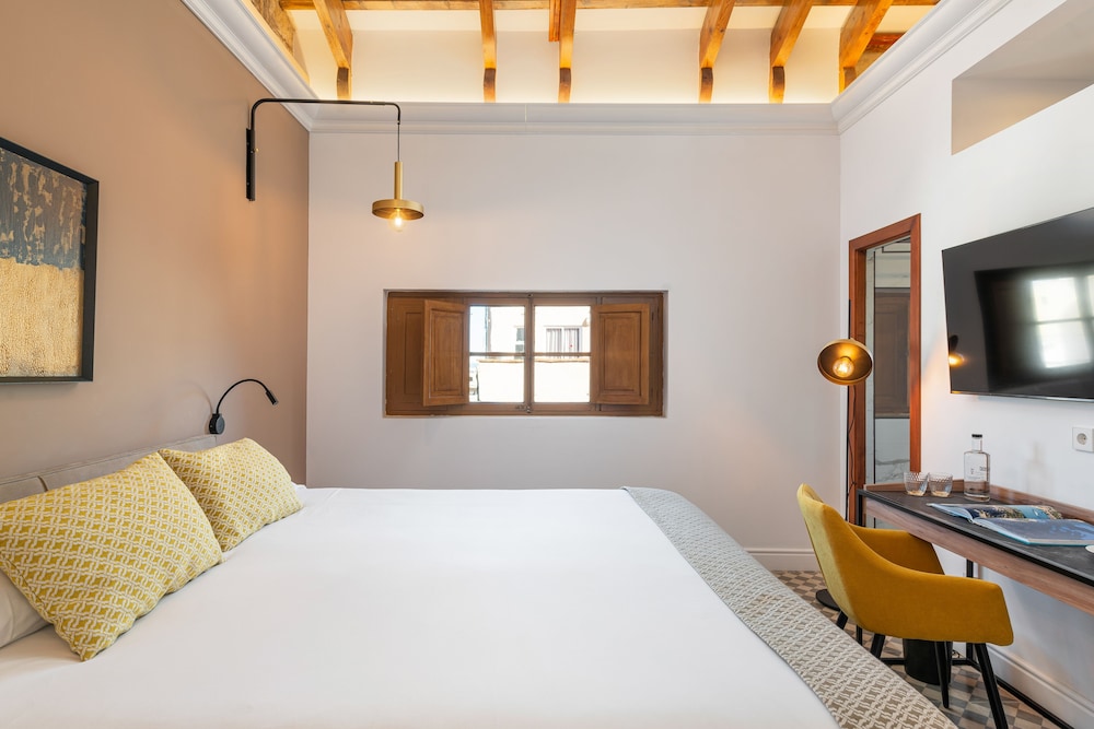bedroom with a white bed, yellow chairs and a flat screen tv