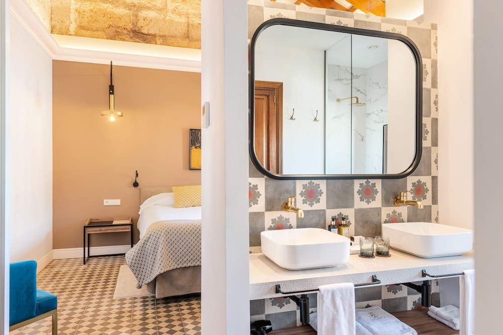 bathroom with two sinks and a bed in the background