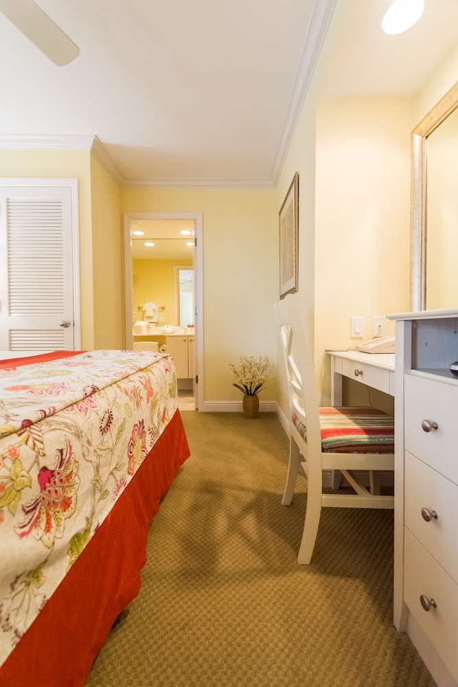 Bedroom with floral bed, desk, and bathroom entrance