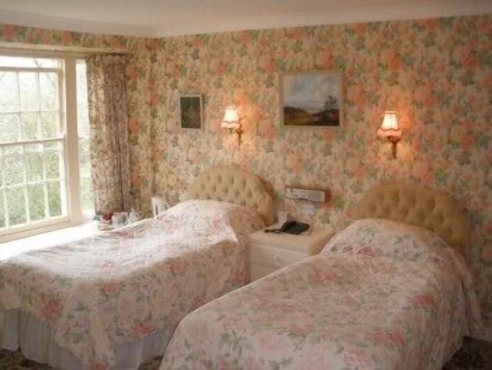 pair of twin beds in a room with floral wallpaper