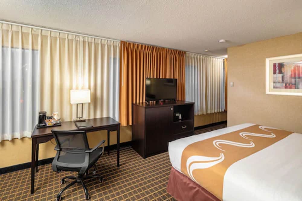 hotel room with a bed, desk, and television