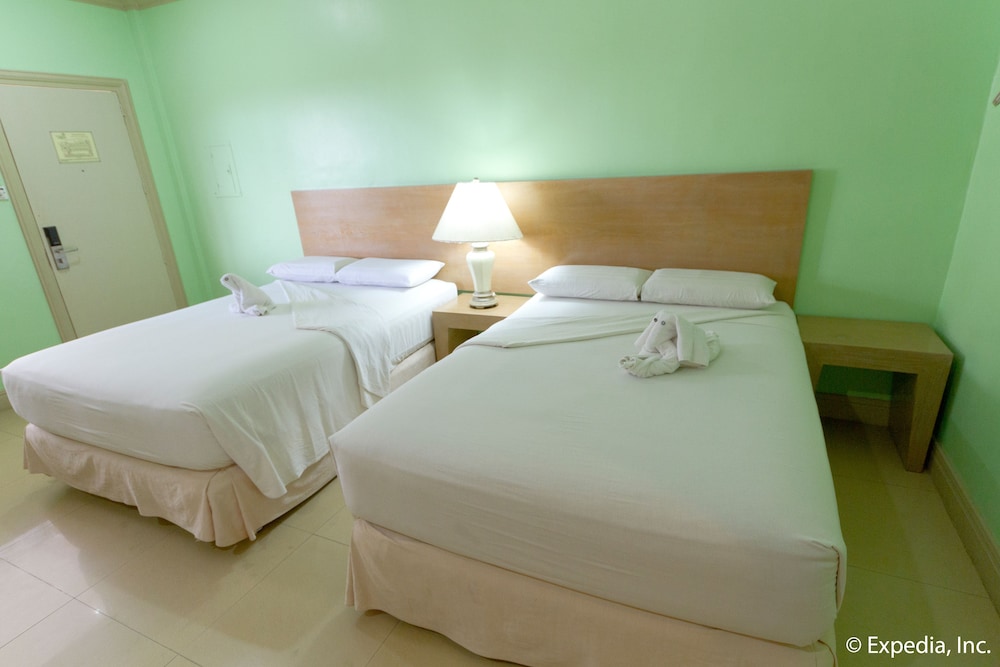 green room with two beds and one has towel on it