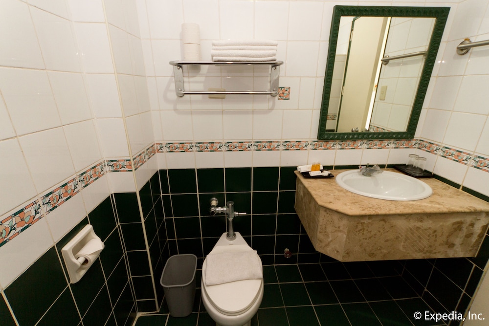 bathroom with green tile and white walls, but the toilet has no seat