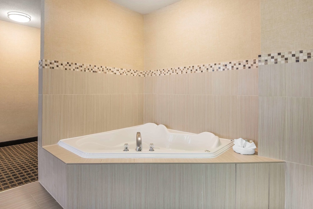 bathroom with a jacuzzi tub and tiled walls