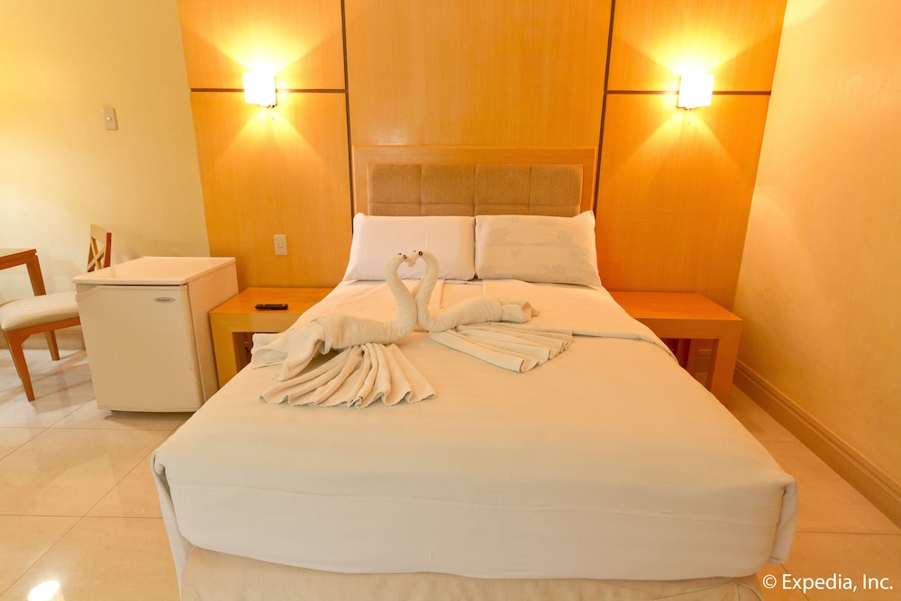 hotel room with swan towels on the bed and two chairs