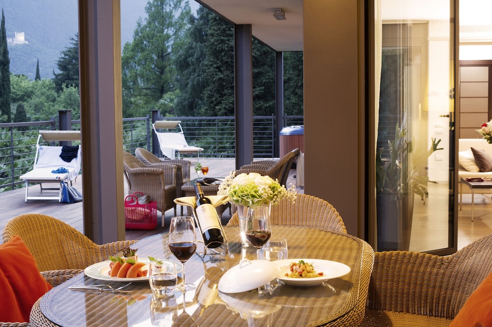 Outdoor terrace dining area with wicker chairs, a glass table, and a mountain view.