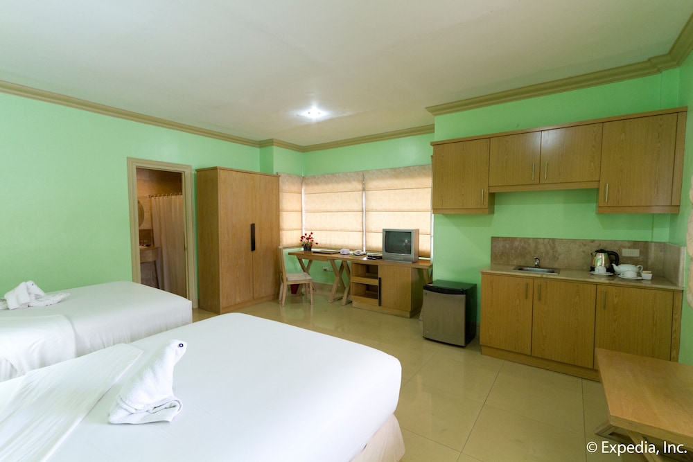 green room with two beds and an open kitchen area