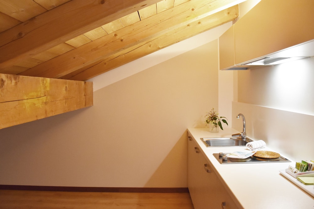 Compact attic kitchenette with sink, cooktop and exposed wooden beams