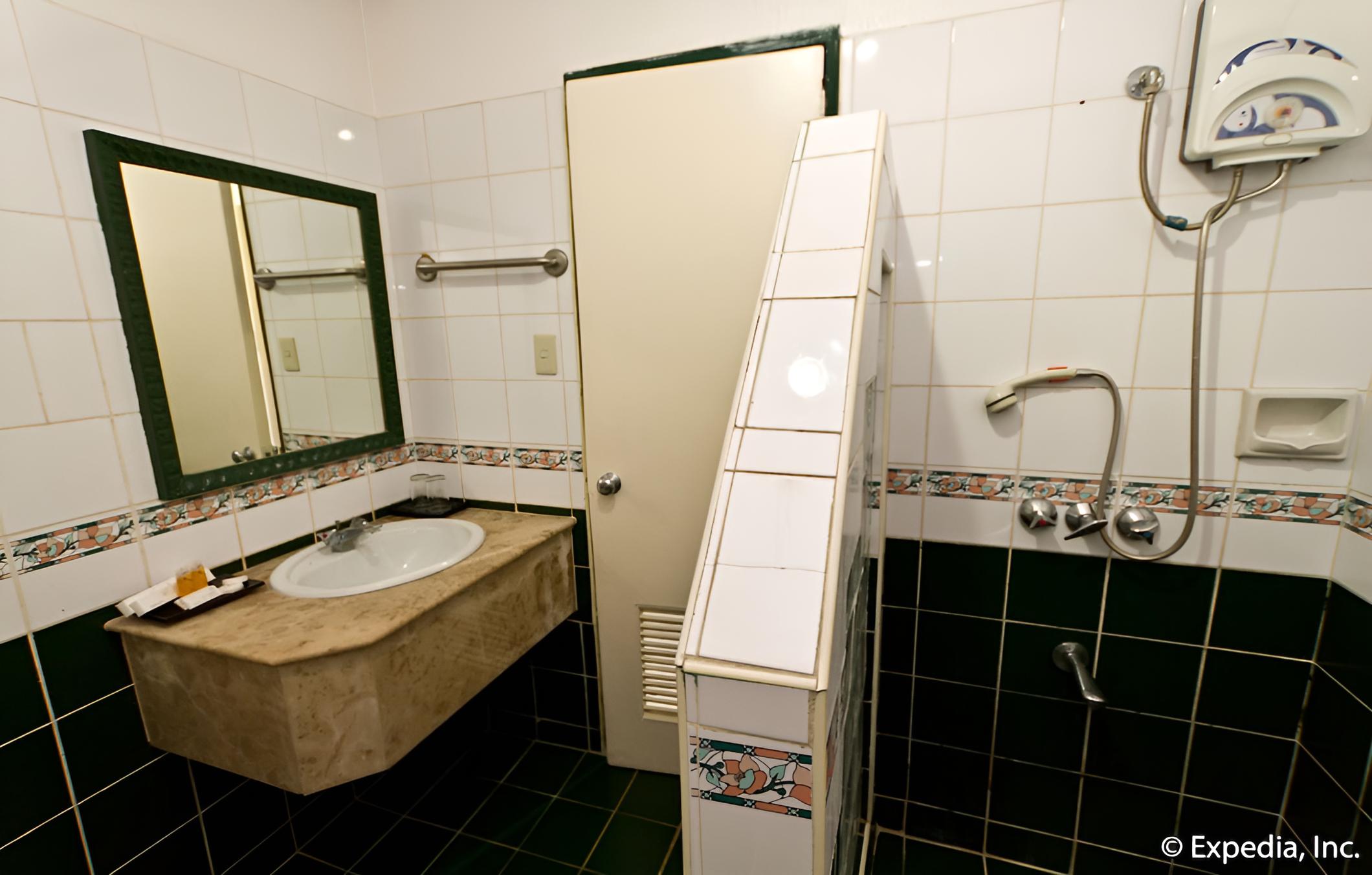 bathroom with green and white tile walls, black flooring
